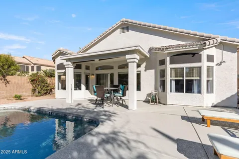 a patio with a table and chairs and potted plants