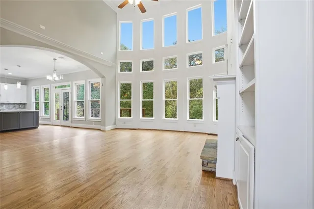 a view of an empty room with wooden floor and a kitchen