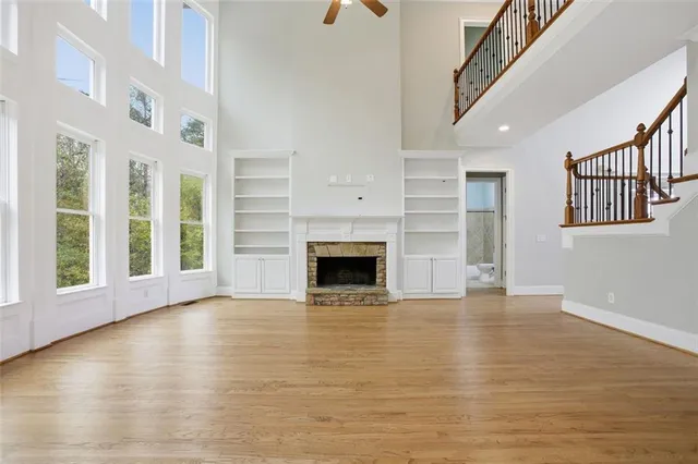 a view of an empty room with wooden floor fireplace and a window