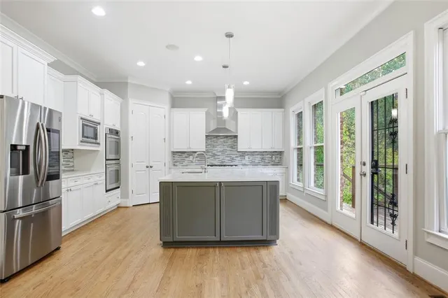a kitchen with kitchen island granite countertop wooden floors and wide window