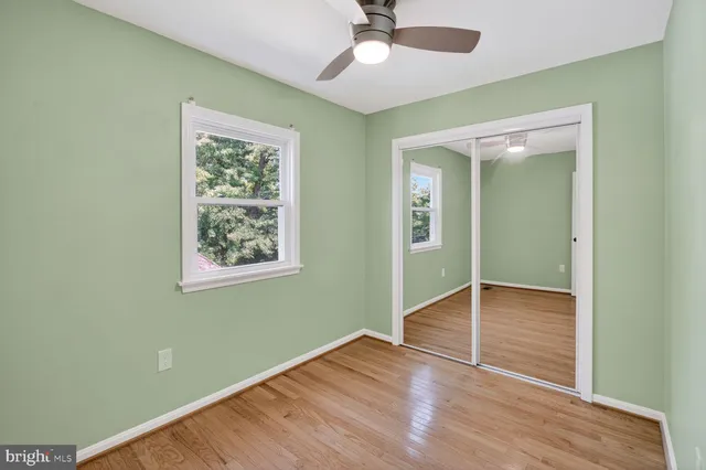 an empty room with wooden floor fan and windows