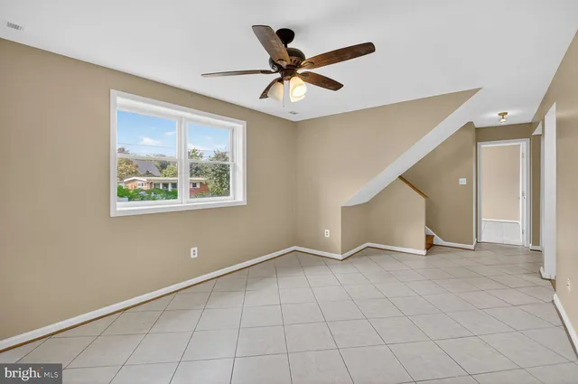 a view of an empty room with chandelier fan
