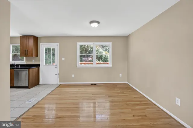 a view of an empty room with kitchen and window