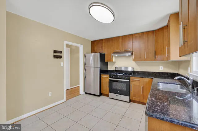 a kitchen with granite countertop a refrigerator and a stove top oven