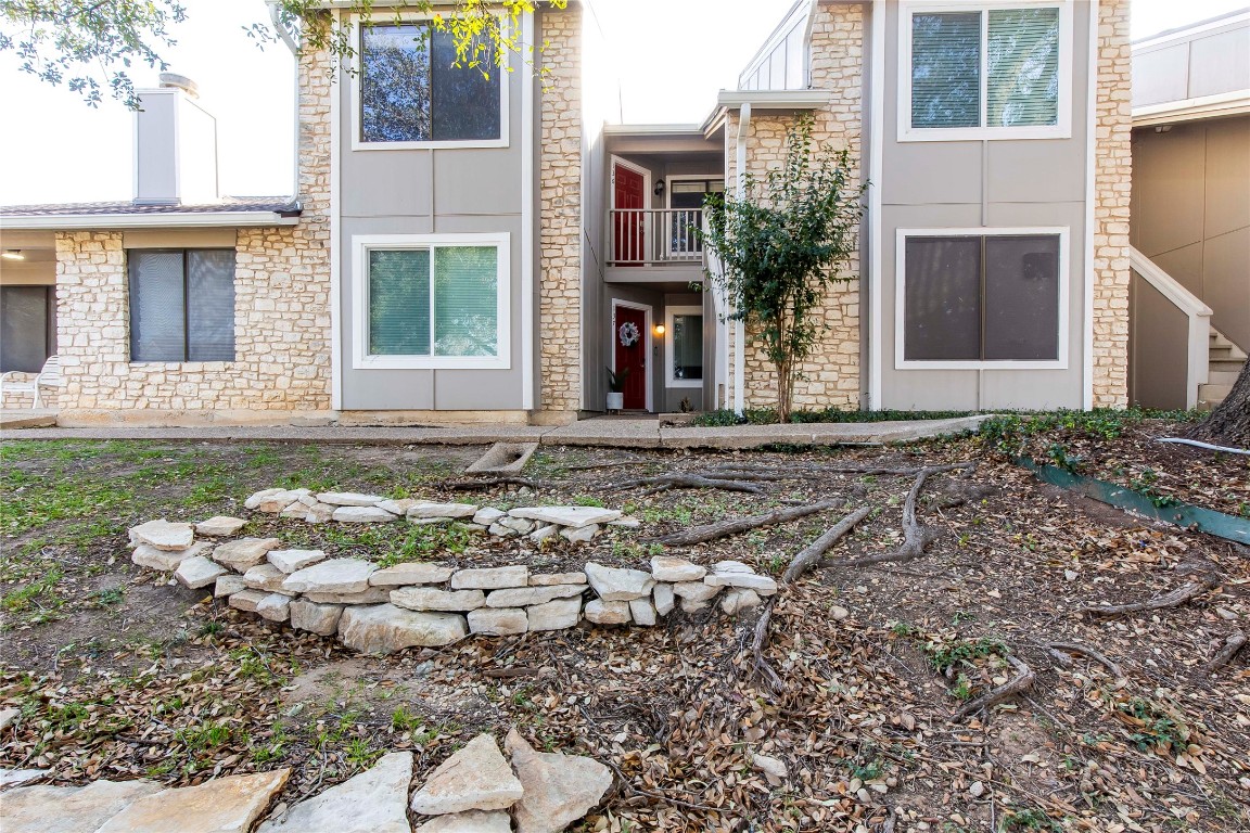 Back of property featuring stone siding and a balcony
