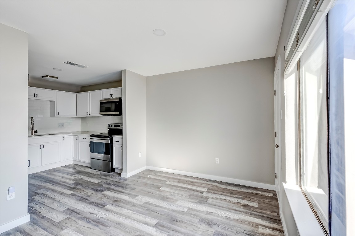 1740 Timber Ridge Road, Unit 136 Austin, TX 78741 - Photo 11 of 32 Kitchen with appliances with stainless steel finishes, white cabinetry, and light wood finished floors