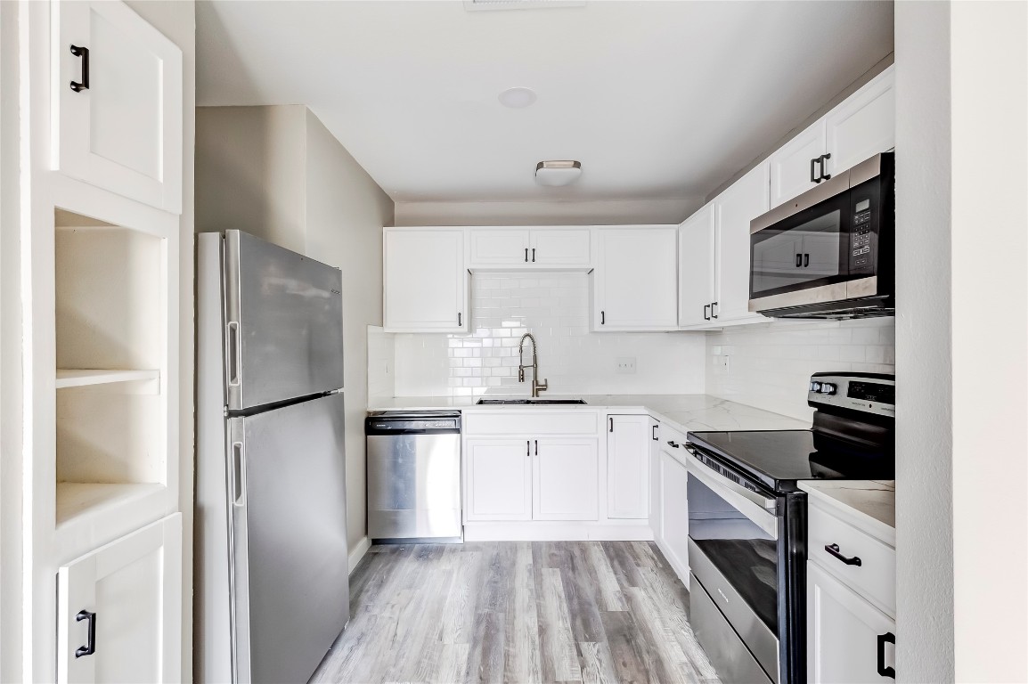 1740 Timber Ridge Road, Unit 136 Austin, TX 78741 - Photo 12 of 32 Kitchen with stainless steel appliances, backsplash, and white cabinetry