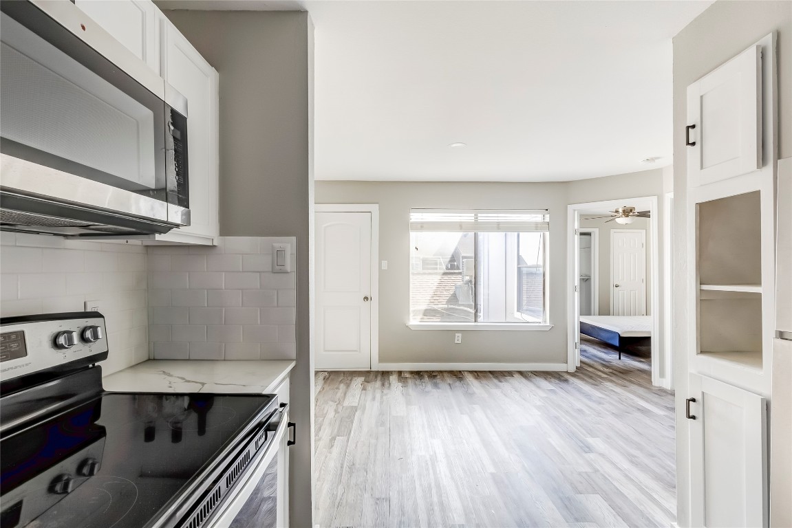 1740 Timber Ridge Road, Unit 136 Austin, TX 78741 - Photo 15 of 32 Kitchen featuring stainless steel appliances, tasteful backsplash, white cabinetry, and light wood-style floors