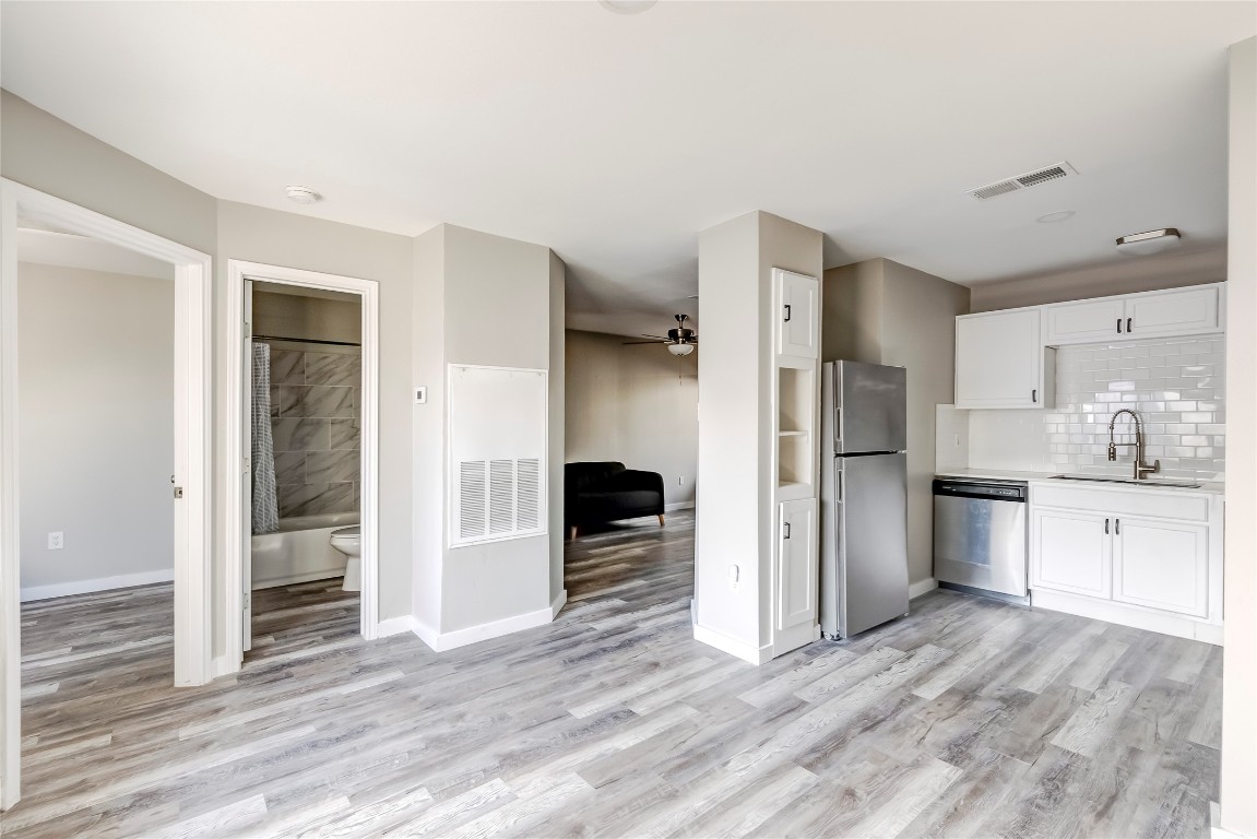 1740 Timber Ridge Road, Unit 136 Austin, TX 78741 - Photo 17 of 32 Kitchen featuring stainless steel appliances, white cabinetry, ceiling fan, light wood finished floors, and decorative backsplash