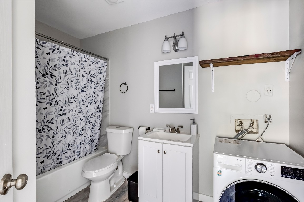 1740 Timber Ridge Road, Unit 136 Austin, TX 78741 - Photo 21 of 32 Bathroom with washer / clothes dryer, vanity, shower / tub combo with curtain, and wood finished floors