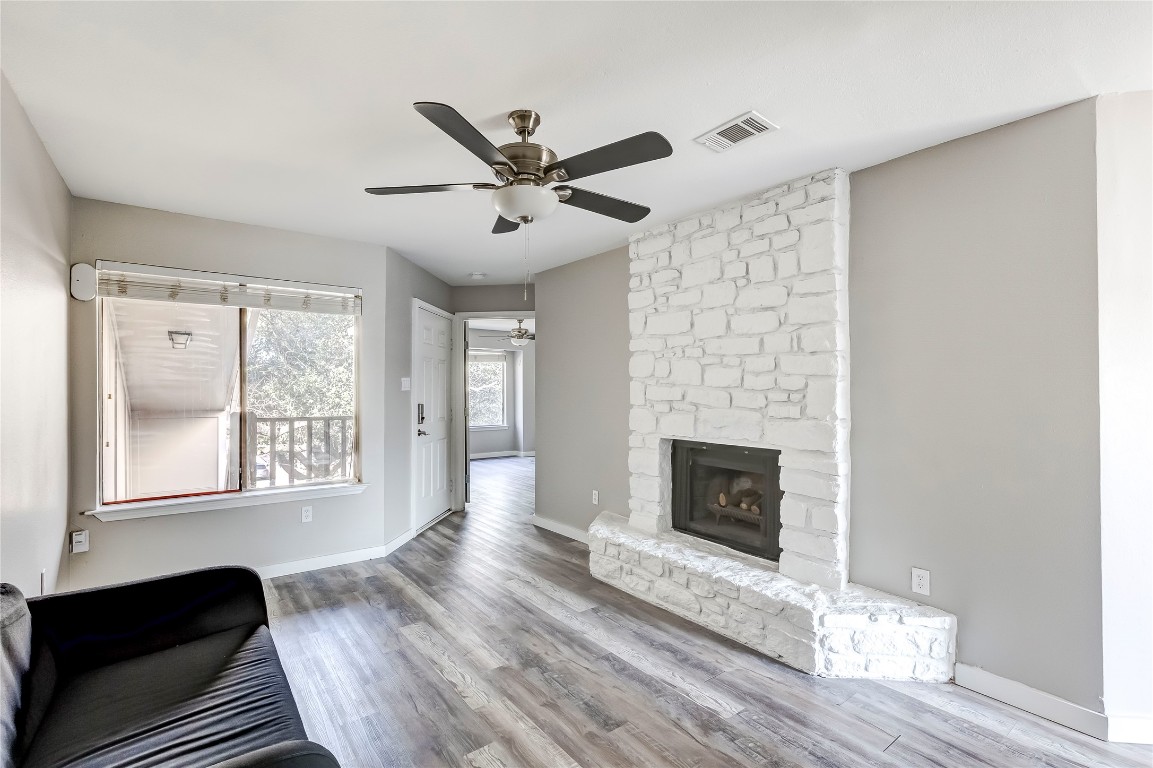 1740 Timber Ridge Road, Unit 136 Austin, TX 78741 - Photo 9 of 32 Unfurnished living room featuring ceiling fan, wood finished floors, and a stone fireplace