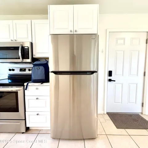 a kitchen with a refrigerator a stove top oven and white cabinets