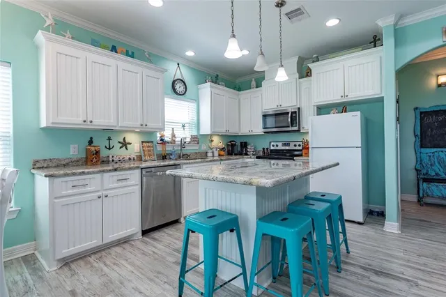a kitchen with kitchen island granite countertop a sink a counter space stainless steel appliances and cabinets