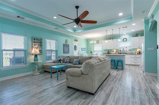 a living room with furniture kitchen view and a wooden floor