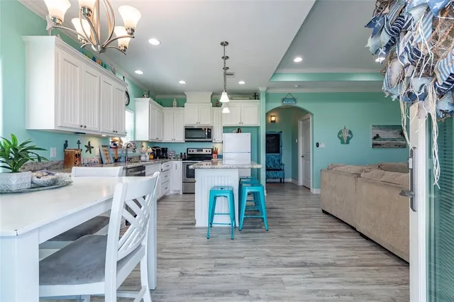 a kitchen with kitchen island granite countertop wooden floors and white cabinets