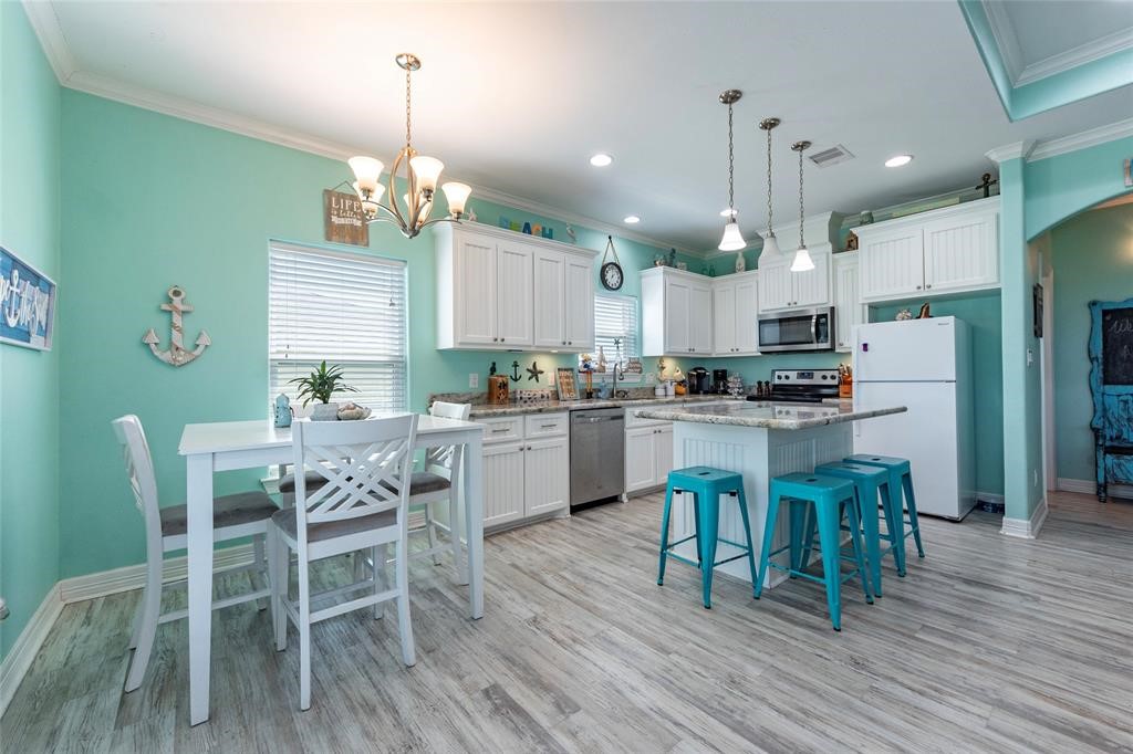 987 Surf Crystal Beach Crystal Beach, TX 77650 - Photo 8 of 45 a kitchen with kitchen island granite countertop wooden floors and white cabinets