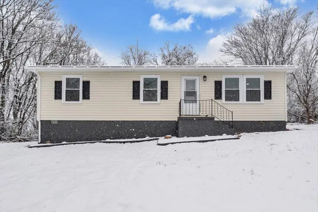 a front view of a house with a yard covered in snow