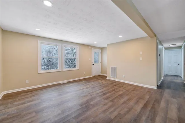 a view of an empty room with wooden floor and window