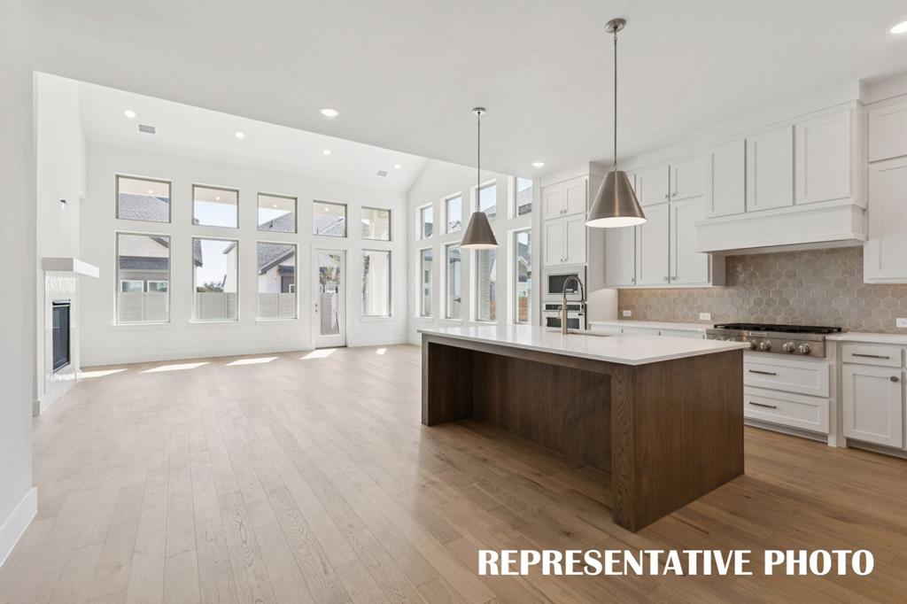 3909 Launch Road McKinney, TX 75071 - Photo 5 of 17 a kitchen with stainless steel appliances granite countertop a sink a oven a stove and white cabinets