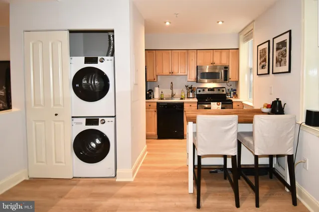 a kitchen with stainless steel appliances a dining table chairs and a refrigerator