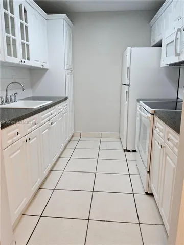 a kitchen with a sink a refrigerator and cabinets