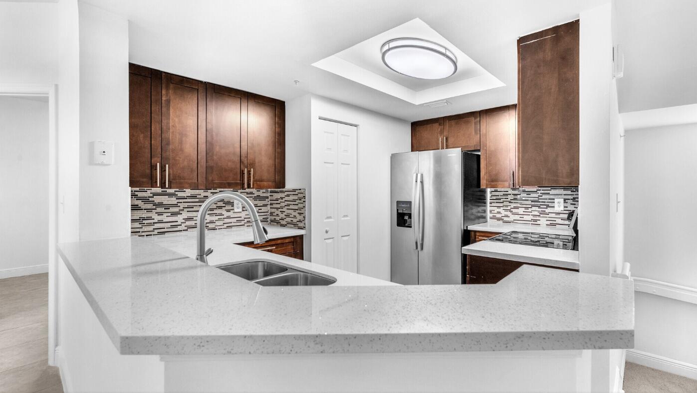 20889 St Andrews Boulevard Boca Raton, FL 33433 - Photo 3 of 5 a kitchen with stainless steel appliances granite countertop a sink and a refrigerator