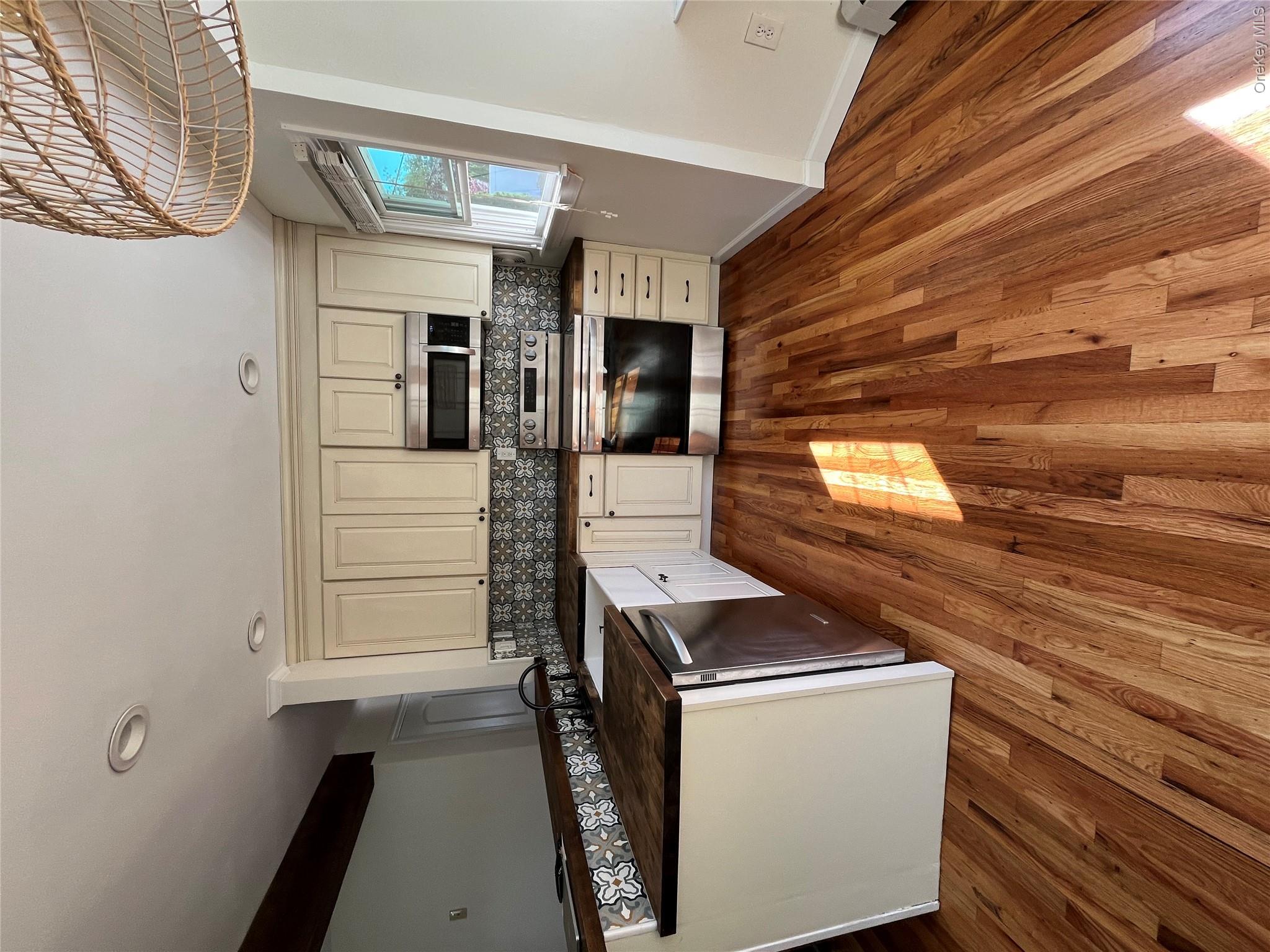 338 Carnation Road West Islip, NY 11795 - Photo 13 of 18 Kitchen featuring wood-finish flooring, cream-toned cabinetry with dark hardware, stainless steel appliances, and patterned tile backsplash