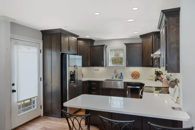 a kitchen with stainless steel appliances a table chairs and refrigerator