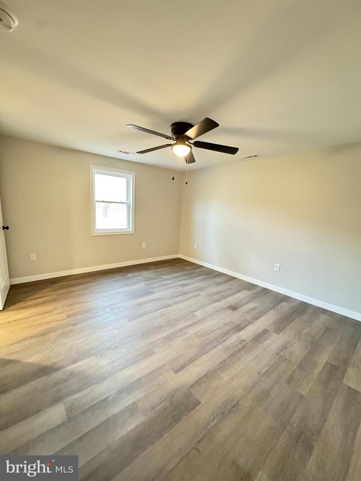 7178 Jericho Road Ruther Glen, VA 22546 - Photo 13 of 18 an empty room with wooden floor fan and windows