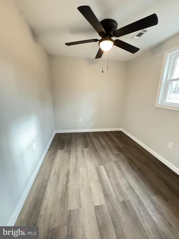 an empty room with wooden floor a ceiling fan and windows