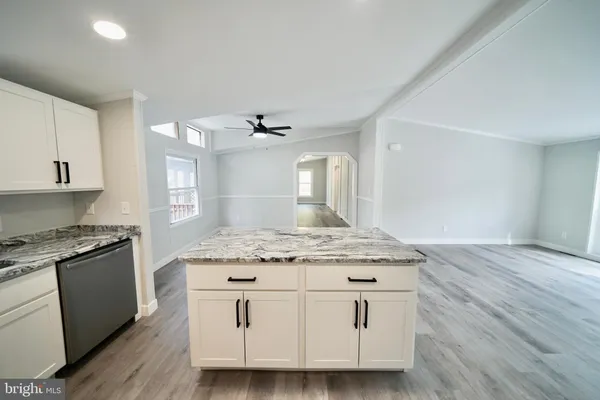 a kitchen with granite countertop a sink cabinets and wooden floor