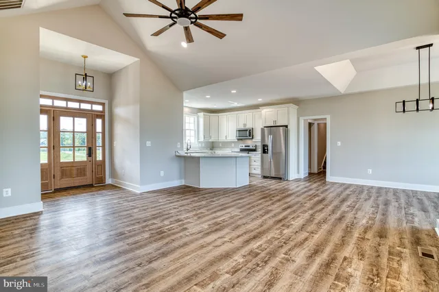 an empty room with wooden floor fan and windows