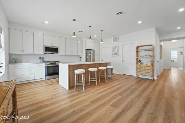 a large kitchen with cabinets chairs and wooden floor