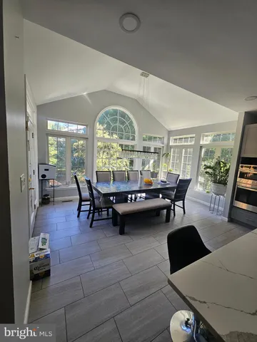 a large living room with couches a flat tv screen and a dining table with wooden floor