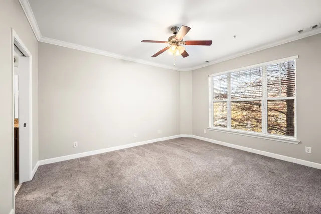 an empty room with windows and fan