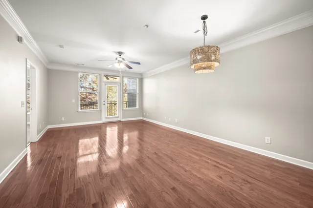 an empty room with wooden floor chandelier and windows
