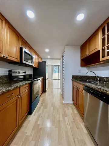 a large kitchen with stainless steel appliances granite countertop a stove and a sink