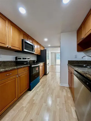 a kitchen with stainless steel appliances granite countertop wooden cabinets a stove top oven a sink and dishwasher