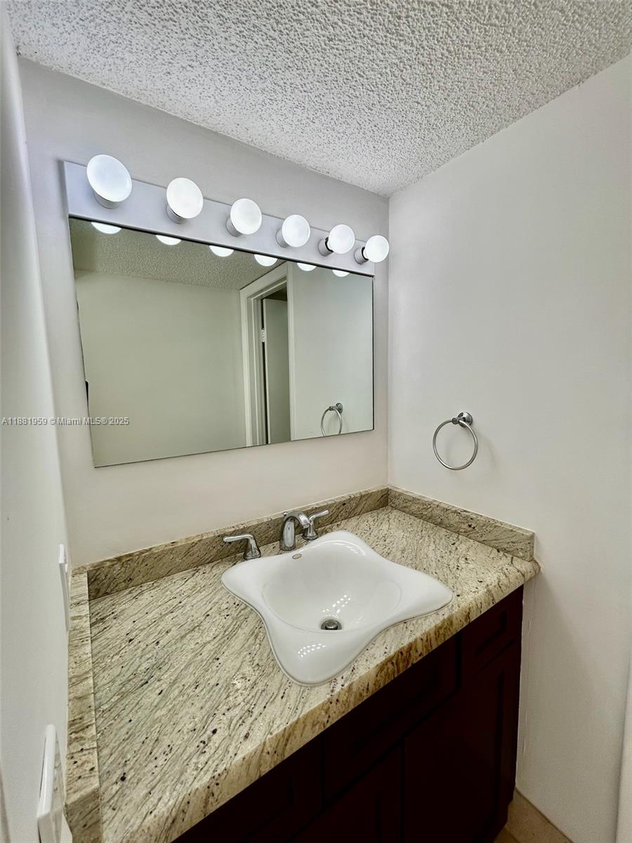 7451 Northwest 16th Street, Unit 304 Plantation, FL 33313 - Photo 27 of 59 a bathroom with a granite countertop sink and a mirror