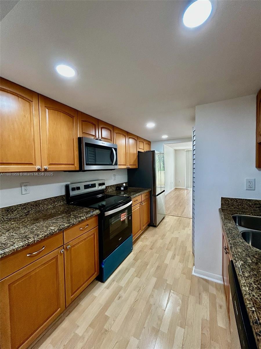 7451 Northwest 16th Street, Unit 304 Plantation, FL 33313 - Photo 3 of 59 a kitchen with stainless steel appliances granite countertop a stove top oven a sink dishwasher a dining table and chairs with wooden floor