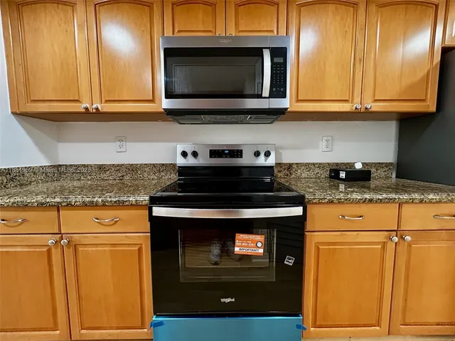 a kitchen with granite countertop cabinets stainless steel appliances and wooden cabinets