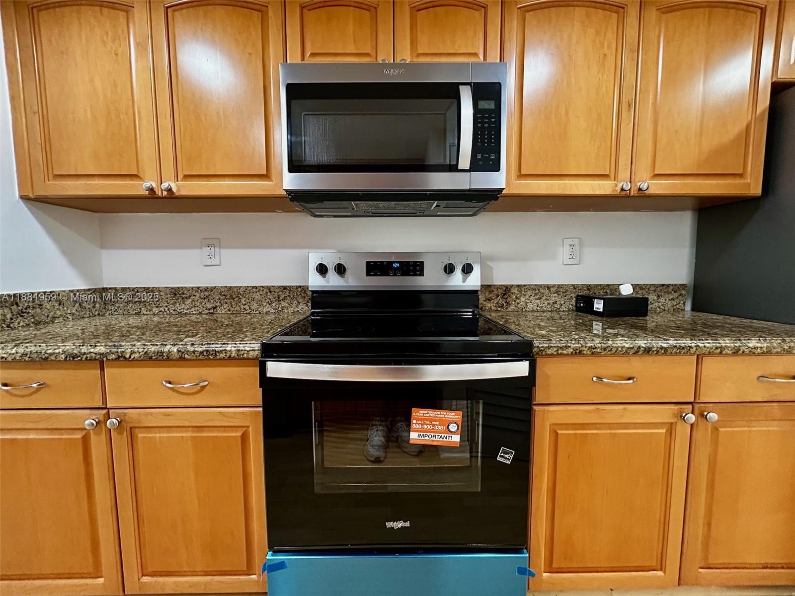 7451 Northwest 16th Street, Unit 304 Plantation, FL 33313 - Photo 4 of 59 a kitchen with granite countertop cabinets stainless steel appliances and wooden cabinets