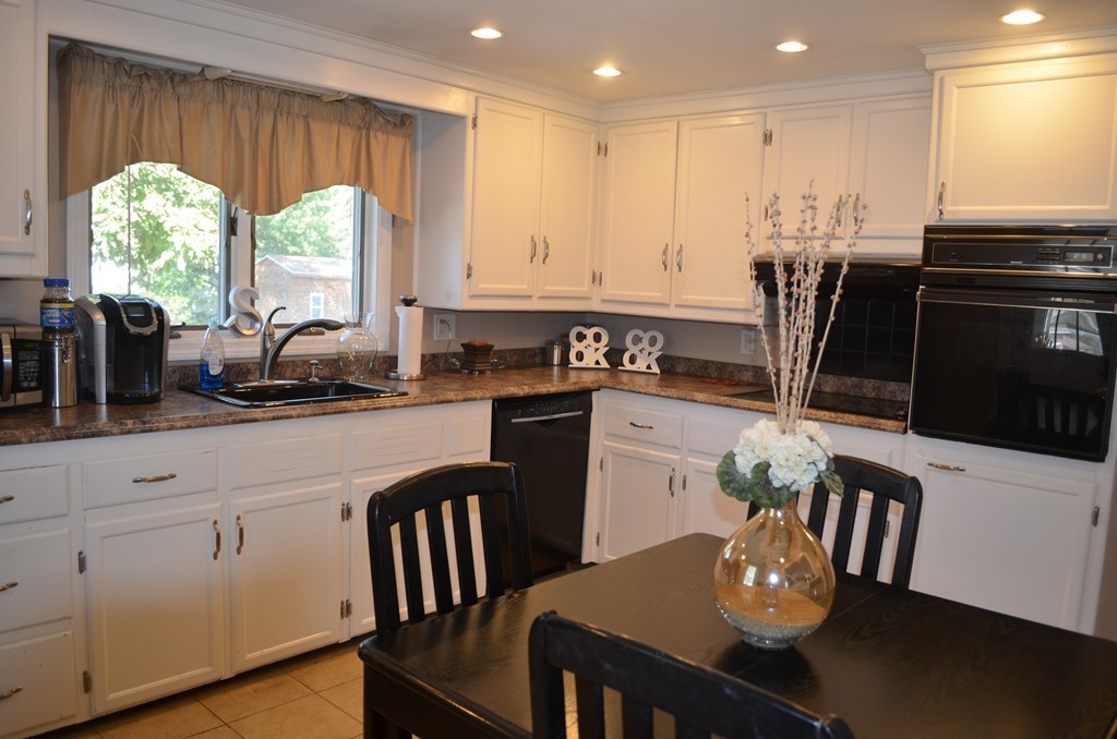 111 Acropolis Road Lowell, MA 01854 - Photo 5 of 15 a kitchen with stainless steel appliances granite countertop a stove a sink a microwave dining table and chairs