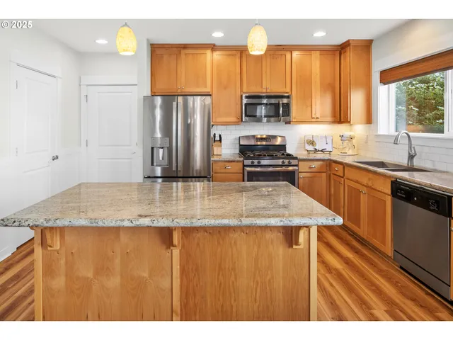 a kitchen with stainless steel appliances granite countertop a sink window and cabinets