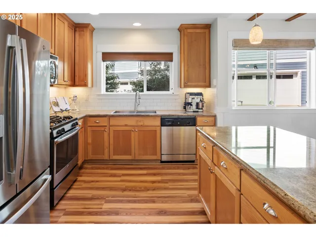 a kitchen with stainless steel appliances granite countertop a stove a sink dishwasher and a refrigerator with wooden cabinets