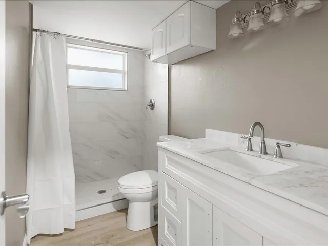 a bathroom with a granite countertop sink a toilet and shower