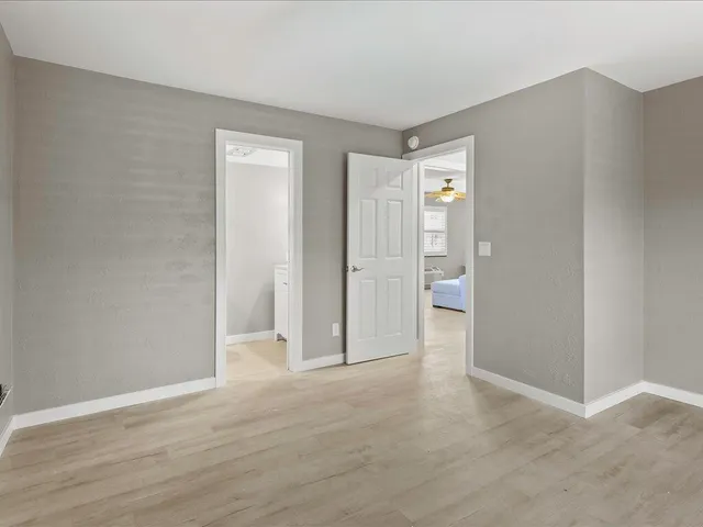 a view of an empty room with wooden floor and closet
