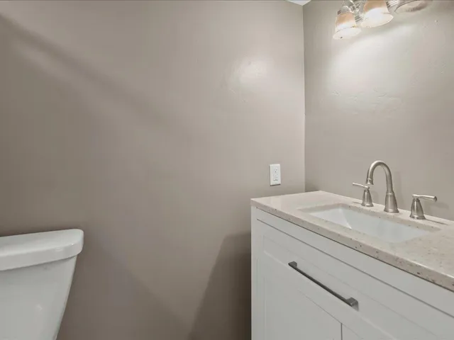 a bathroom with a granite countertop toilet and a sink