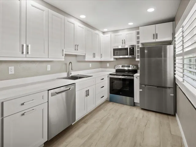 a kitchen with cabinets stainless steel appliances and wooden floor