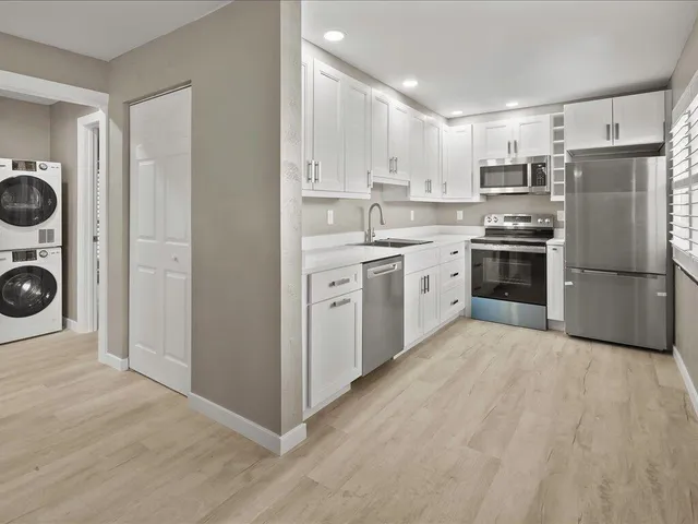 a large kitchen with cabinets stainless steel appliances and wooden floor